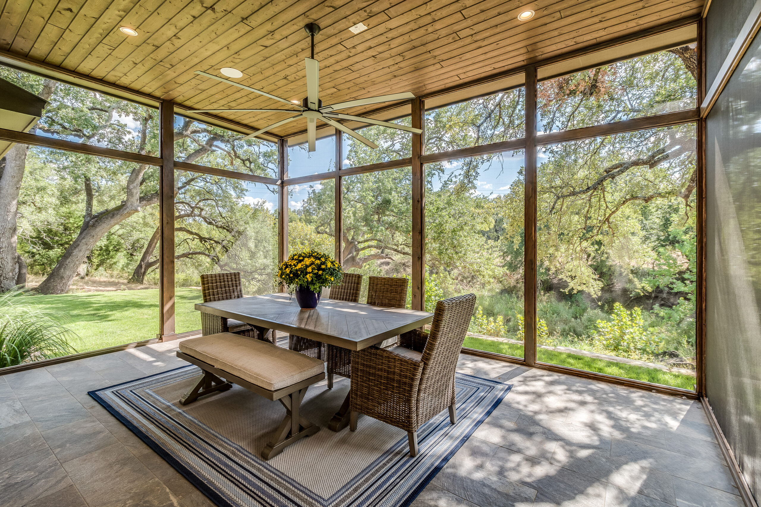 Nice covered patio and sunroom with the outdoor feel without the bugs The interior of a room with wooden roof panels & glass walls.